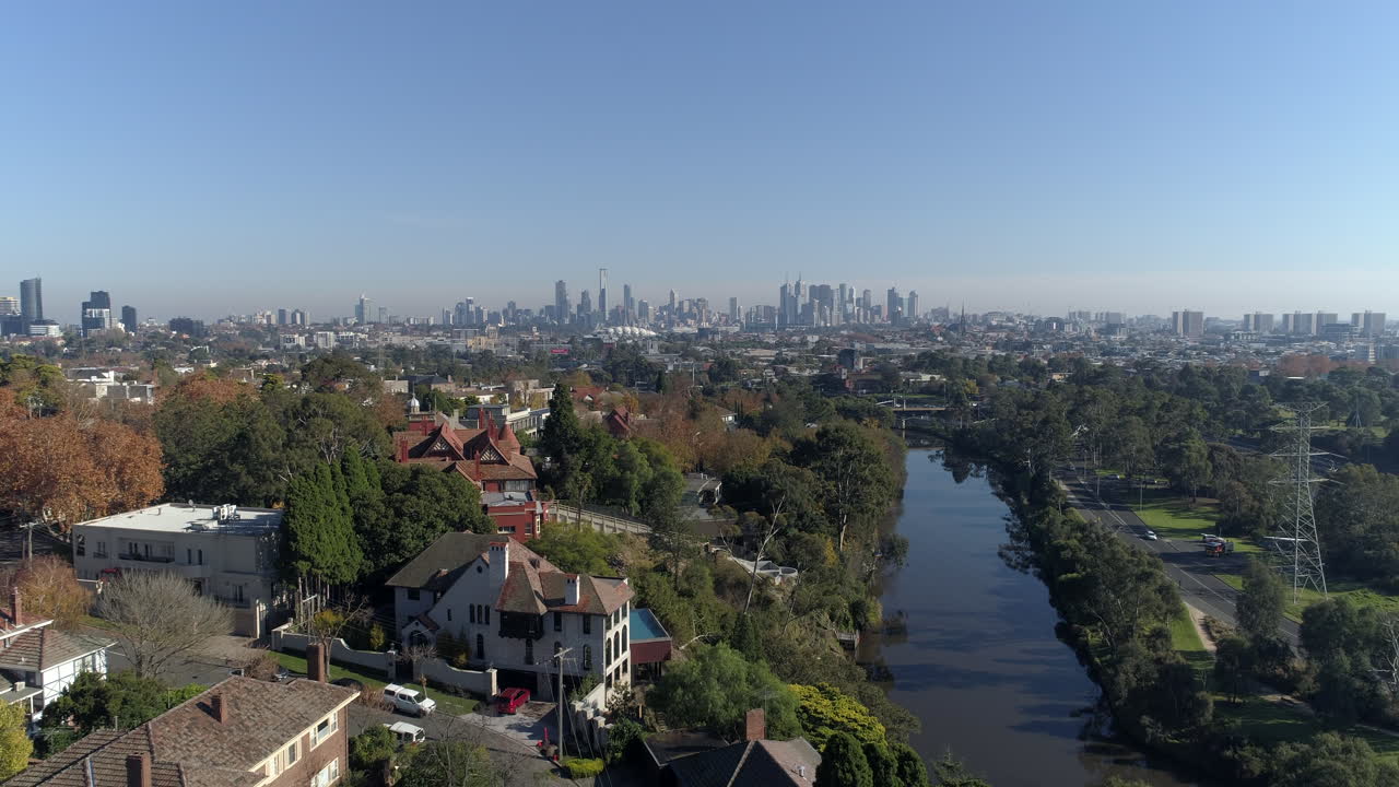 Ripresa aerea lungo il fiume Yarra in un sobborgo di lusso a Melbourne, Australia, con la città all'orizzonte, ripresa con drone.