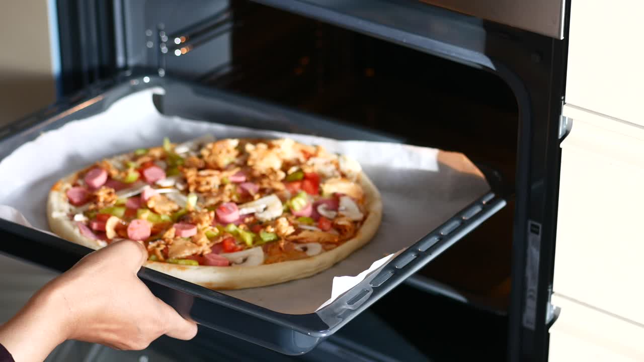 Primo piano di una mano che toglie una pizza dal forno
