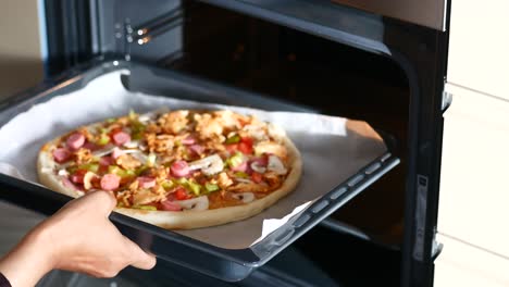 closeup of a hand taking a pizza out of the oven