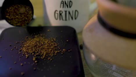 close-up-view-of-finely-ground-coffee-beans-being-poured-on-a-scale-net-to-a-coffee-mug-and-chemix-beaker