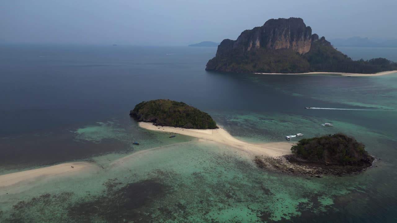 Ko Kai island with turquoise tropical sea and speed boat, Krabi, Thailand. Breathtaking aerial view flight fly reverse drone