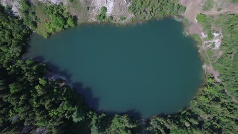 Drone-flying-down-towards-Gypsum-Mine-Lake-near-Cheticamp-in-Nova-Scotia-in-Canada-during-the-day