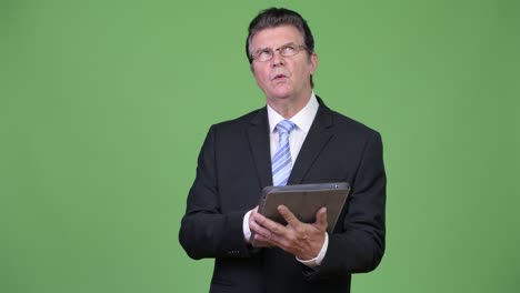 Senior handsome businessman using digital tablet
