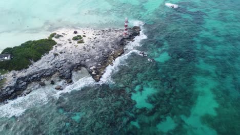 Vista-Aérea-De-Las-Olas-Del-Mar-Caribe-Rompiendo-En-La-Costa-Rocosa-Del-Faro-Antiguo-En-Punta-Cancún,-México