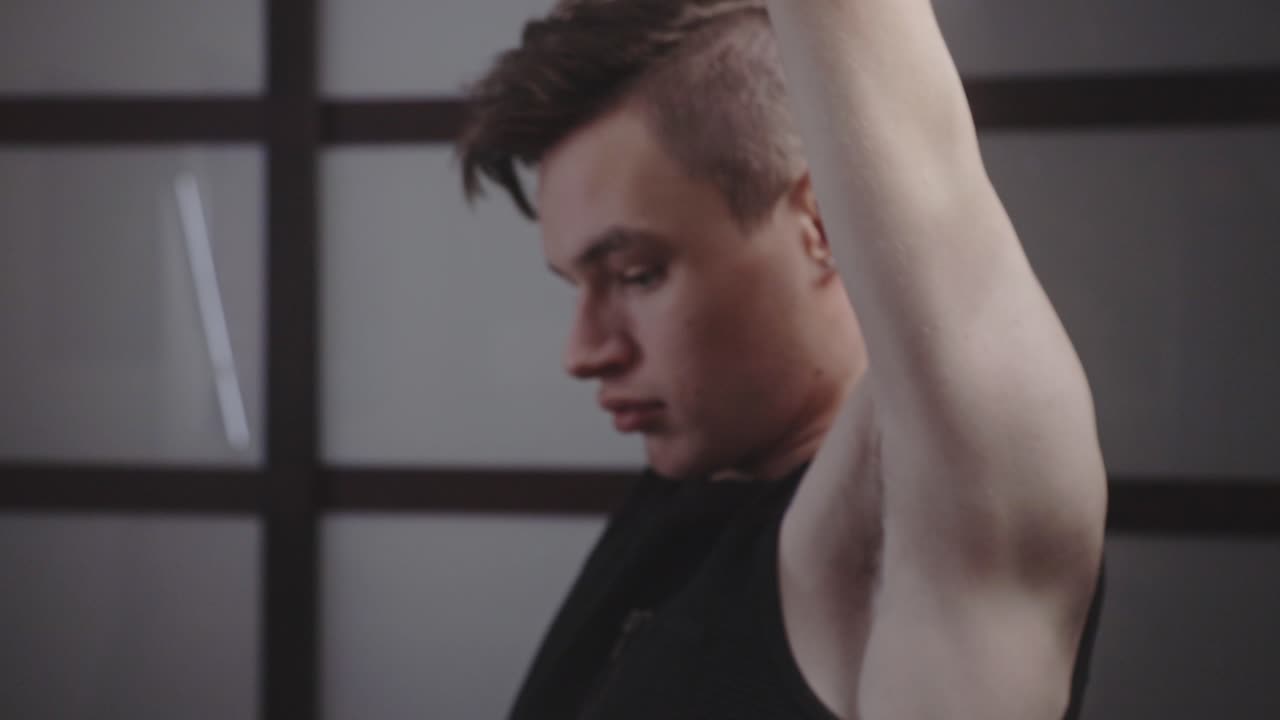 아령을 들고 등 뒤에서 장비를 키우는 젊은 잘생긴 남자의 측면