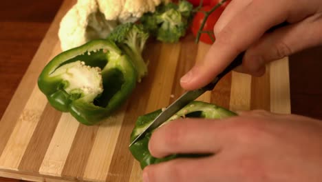 close up of a man cutting red pepper