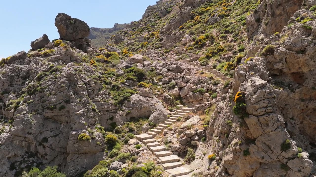 Vista aerea con drone di antichi gradini in pietra che si snodano su un'aspra collina rocciosa in una gola di montagna, Gola di Kourtaliotiko, Grecia