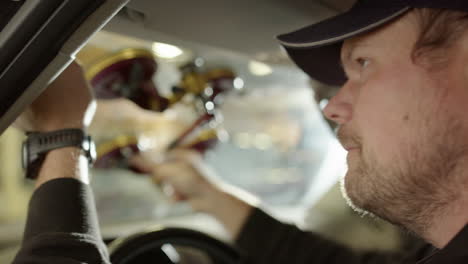 man use apparatus attached to windshield to cut through glue, winds steel wire