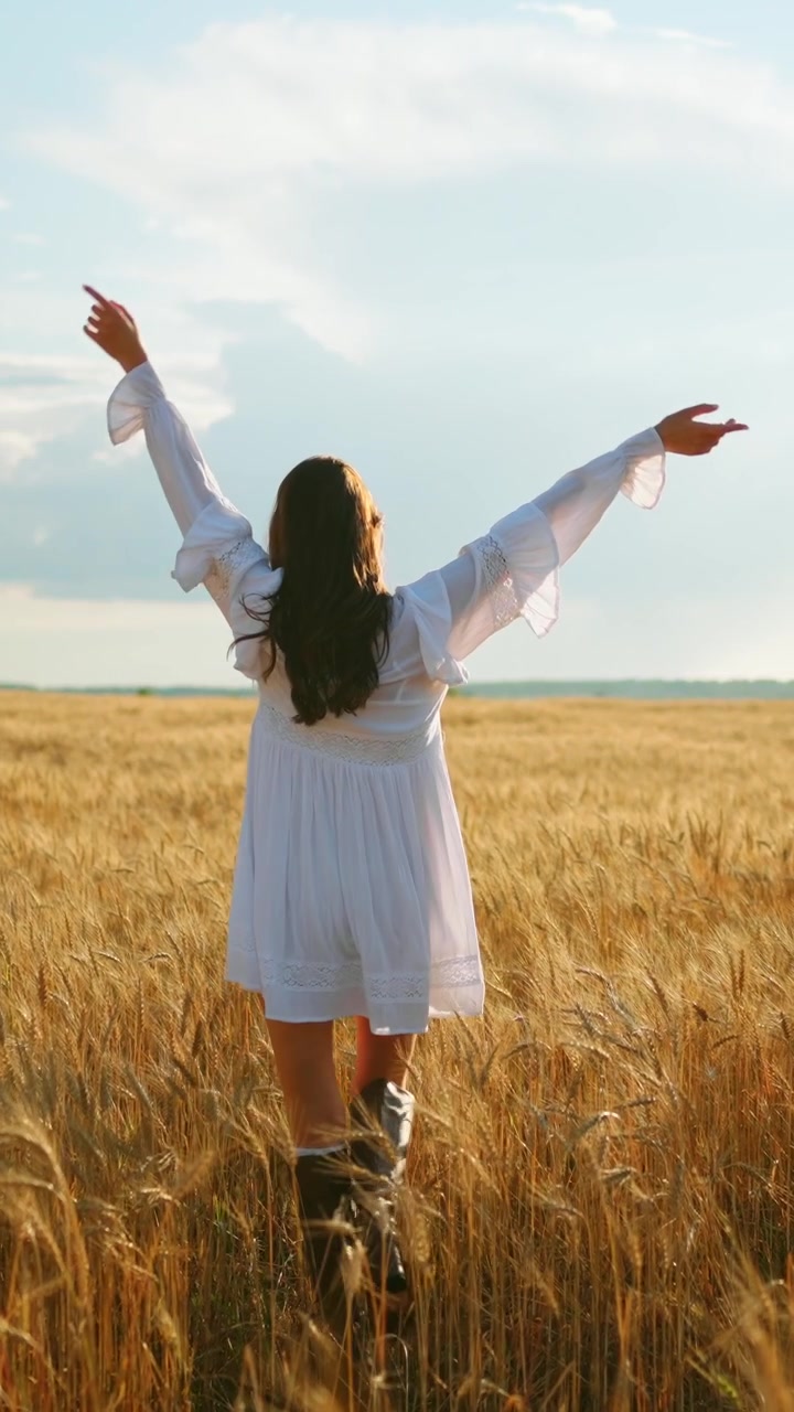 Mujer joven caminando por un campo de trigo dorado al atardecer