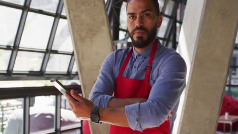 Portrait-of-mixed-race-male-cafe-owner-using-tablet-and-looking-to-camera