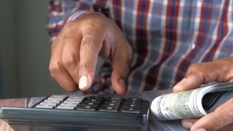 man counting money using a calculator