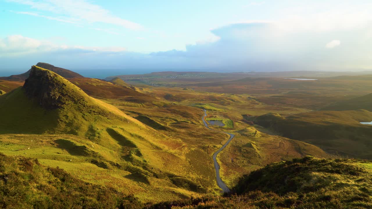se ven ovejas pastando en el deslizamiento de tierra quiraing y los coches pasan por la isla de skye en escocia