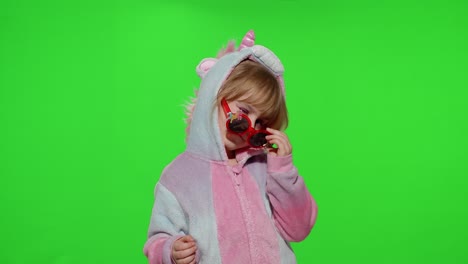 Little-child-girl-smiling,-dancing,-winking,-celebrating-in-unicorn-pajamas-costume-on-chroma-key