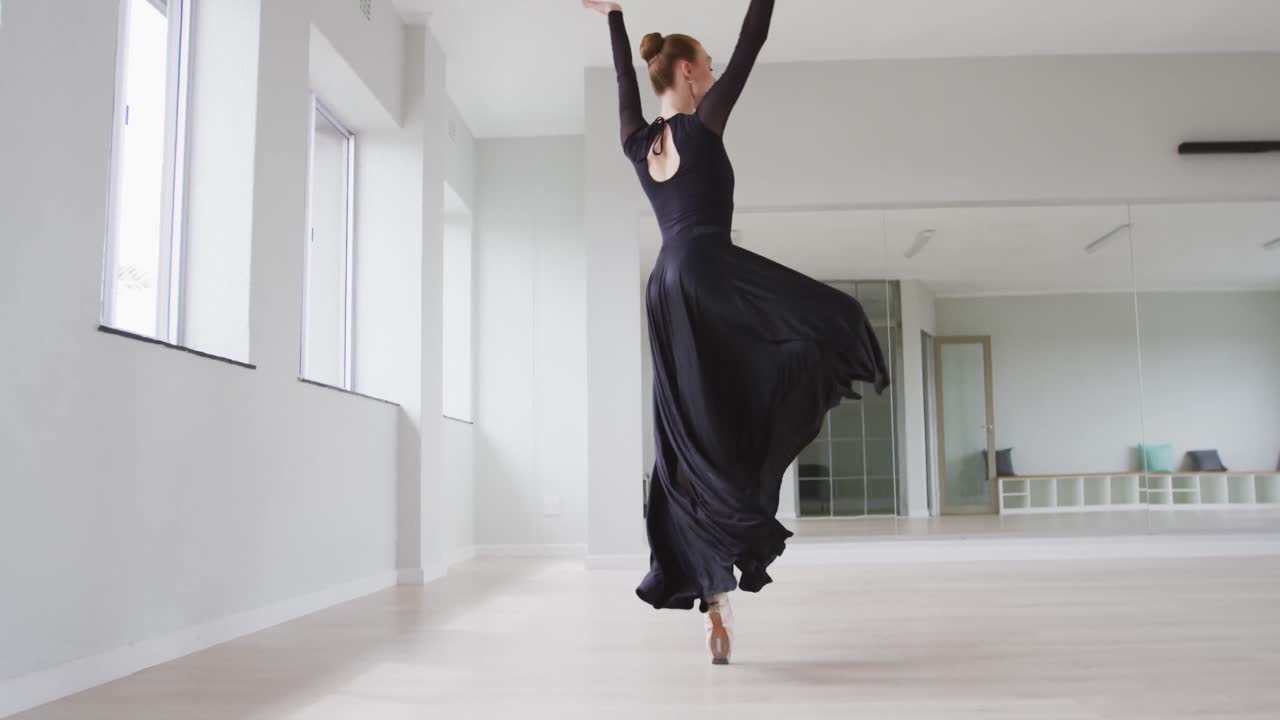 Caucasian female ballet dancer practicing ballet during a dance class in a bright studio