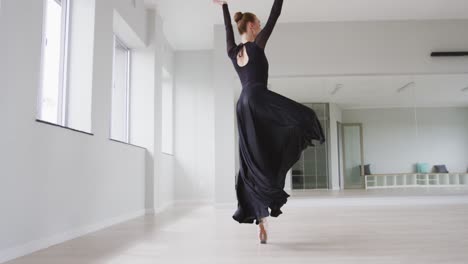 caucasian female ballet dancer practicing ballet during a dance class in a bright studio