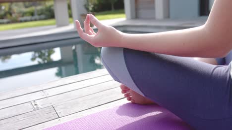 Sección-Baja-De-Una-Mujer-Caucásica-Enfocada-Practicando-Yoga-En-Un-Jardín-Soleado,-Cámara-Lenta