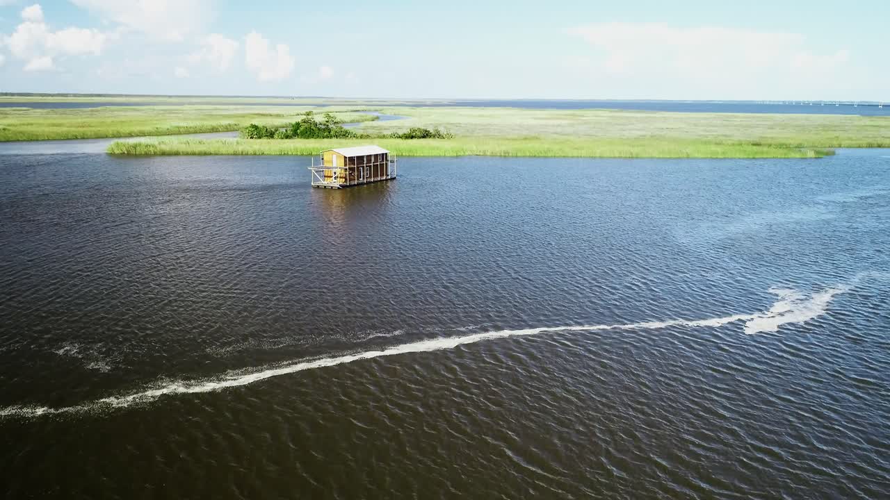 una lancha pasa por una casa flotante en el río apalachicola en apalachicola, florida