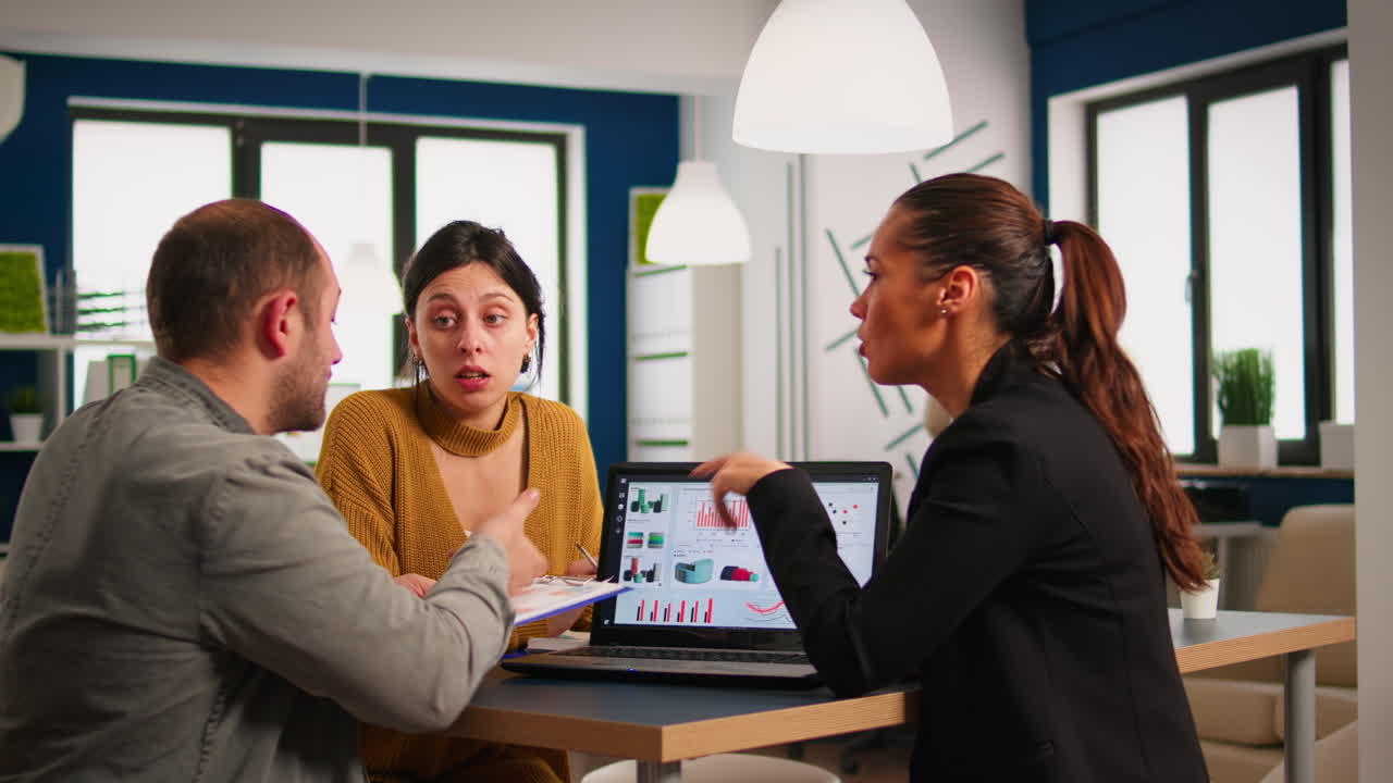 grupo de trabajadores jóvenes hablando, mirando la computadora portátil y analizando datos digitales