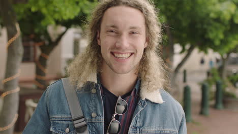 close up portrait of attractive young caucasian man student smiling cheerful looking at camera enjoying independent lifestyle in urban city background