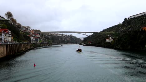 boat navigating in douro river towards ponte infante dom henrique on a cloudy day