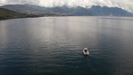 Vista-Aérea-De-Un-Bote-Pequeño-En-Un-Hermoso-Lago-Con-Montañas-A-Lo-Lejos