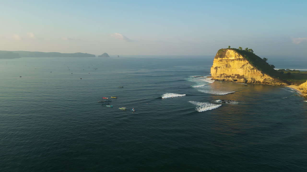 Vista aerea panoramica dello spot per il surf di Gerupuk con surfisti che cavalcano l'onda, scogliere in mezzo al mare di Bali.
