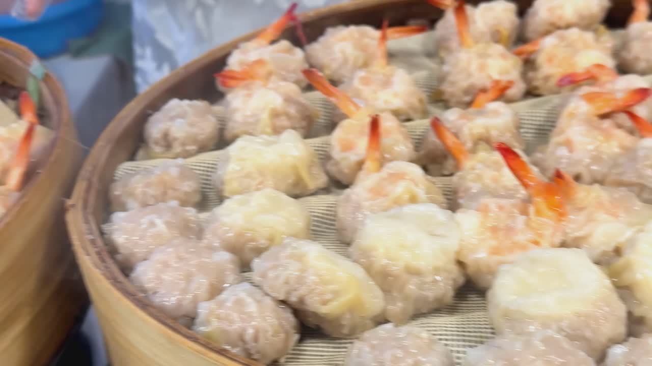 Close-up of steamed dumplings with visible prawn tails in a bamboo steamer basket, showcasing traditional preparation.