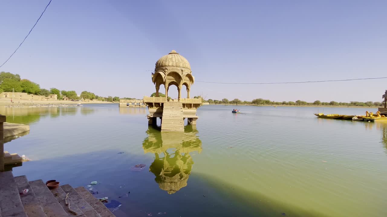 Gadsisar Lake in Jaisalmer sparkles under the golden Rajasthan sun, mirroring ancient temples, calm waters, and elegant pavilions offering a serene escape in the heart of the desert's timeless beauty.