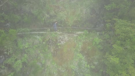 madeira, portugal - male backpacker walking at the trail on the side of the lush mountain on a foggy day - aerial drone shot