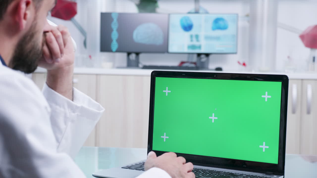 Doctor working on laptop with green screen in lab