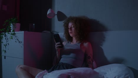 woman using smartphone in bed at night