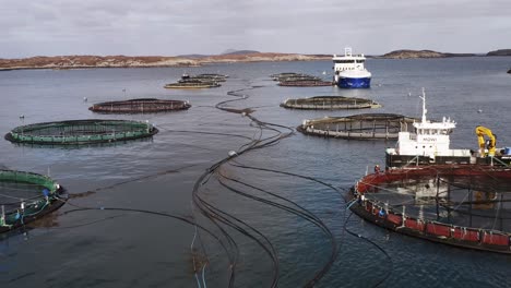 toma aérea de una granja de peces de las hébridas siendo mantenida por un barco de pozo