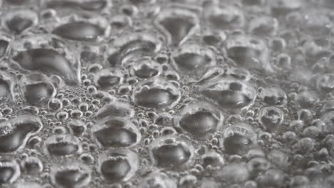 Close-Up-of-Intensely-Boiling-Water-with-Strong-Bubbles-and-Rising-Smoke-in-a-Pan