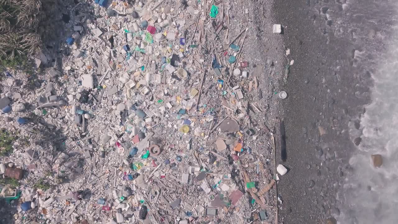 Beach covered in plastic marine debris causing climate change and environmental problems. Top down aerial drone view