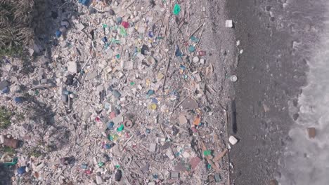 beach covered in plastic marine debris causing climate change and environmental problems. top down aerial drone view