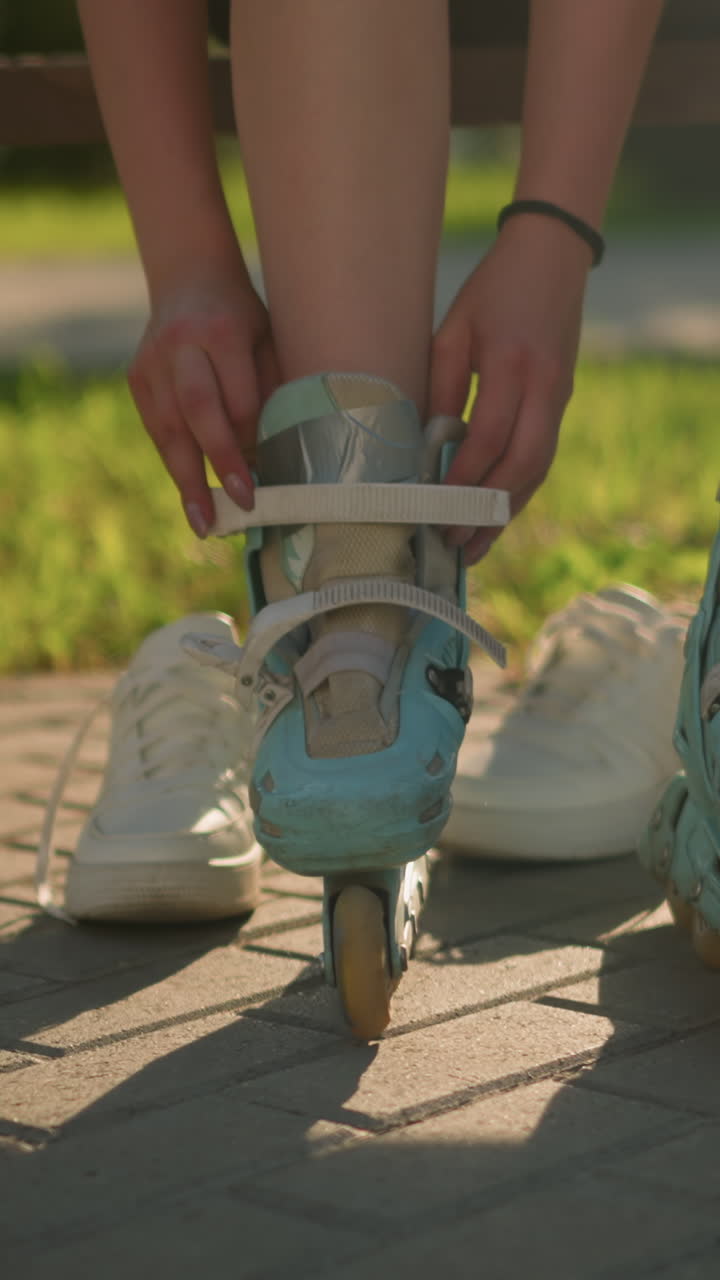 오른손에 검은색 팔와 함께 벤치에 앉아있는 시안 롤러 스케이트에 대한 개별 조정 의 다리 시각, 뒷면에  스니커, 따뜻한 빛이 그림자를 던집니다.