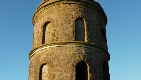 Stone-tower-monument,-tilt-up-with-blue-sky