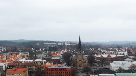 Majestic-township-skyline-with-church-tower-in-Sweden,-aerial-tilt-down-shot
