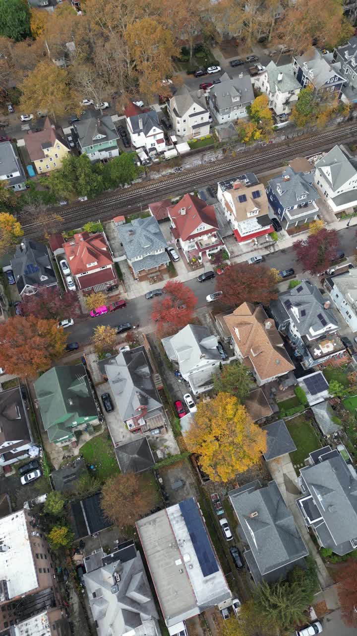 High aerial angle of Brooklyn in autumn showing blocks of row homes, sidewalks, and trees in peak foliage. Bright colors highlight urban symmetry and seasonal change
