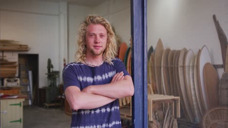 caucasian male surfboard maker leaning on a door frame of the entrance with his arms crossed