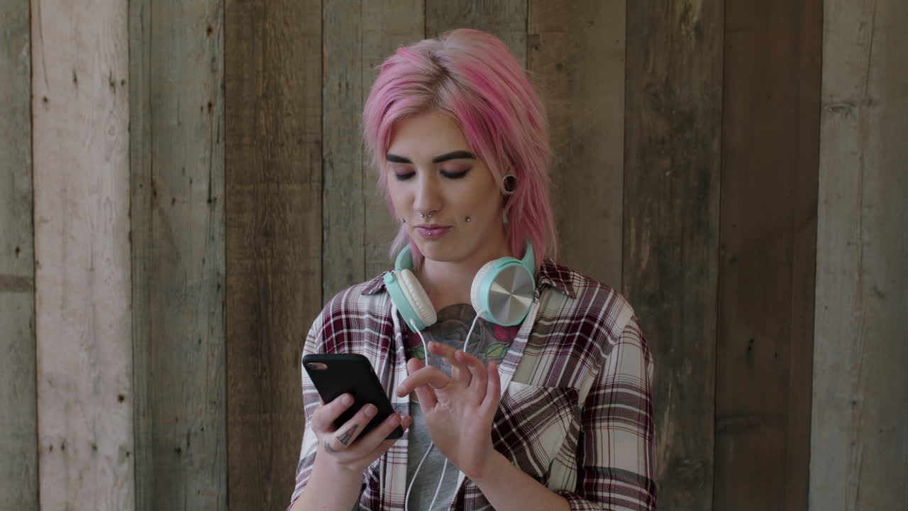 retrato de una joven punk de una mujer atractiva con un peinado rosa posando tomando una foto selfie utilizando la tecnología de la cámara del teléfono inteligente