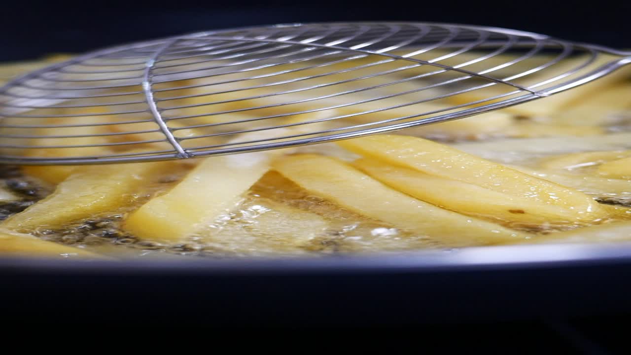Primo piano di patatine fritte che friggono in una padella