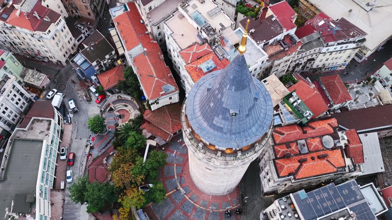 Splendido video drone della Torre di Galata a Istanbul, che mostra il tetto conico dell'iconica torre in pietra, densi edifici con tetti rossi e una suggestiva fusione di architettura urbana antica e moderna.