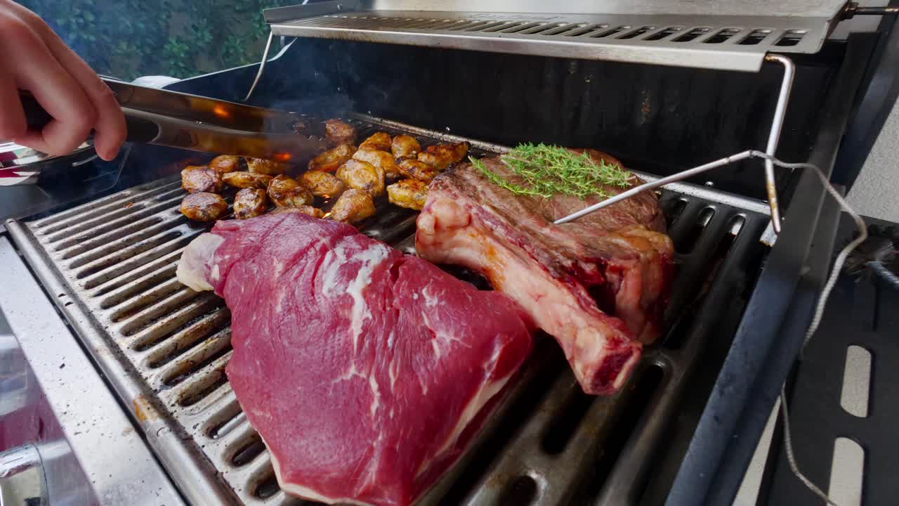 Grilling steaks with probe thermometer and chicken wings on the barbecue. Close up shot