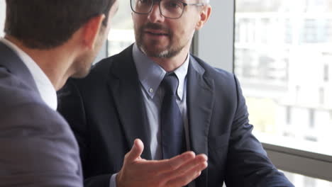 two businessmen using digital tablet in office meeting