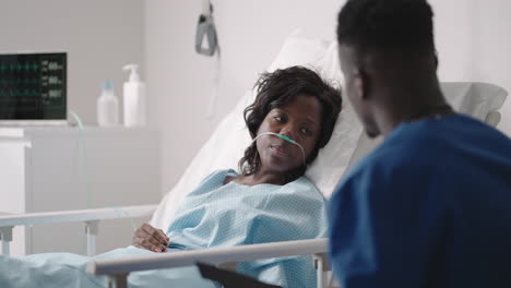 a young african-american male doctor is talking to a patient. a black woman patient talks to a doctor