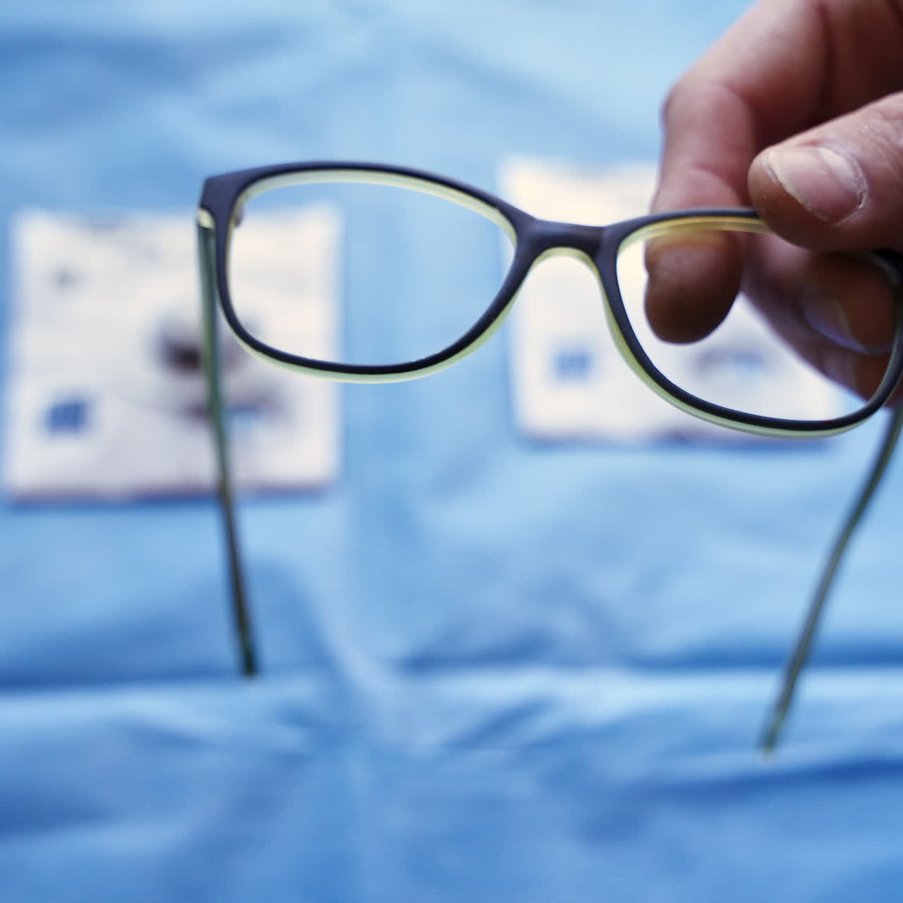Specialist puts lenses into black frame of eyeglasses. Production of spectacles in the laboratory. Making eyeglasses.