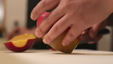 person cutting a fresh ripe sweet mango using a sharp knife