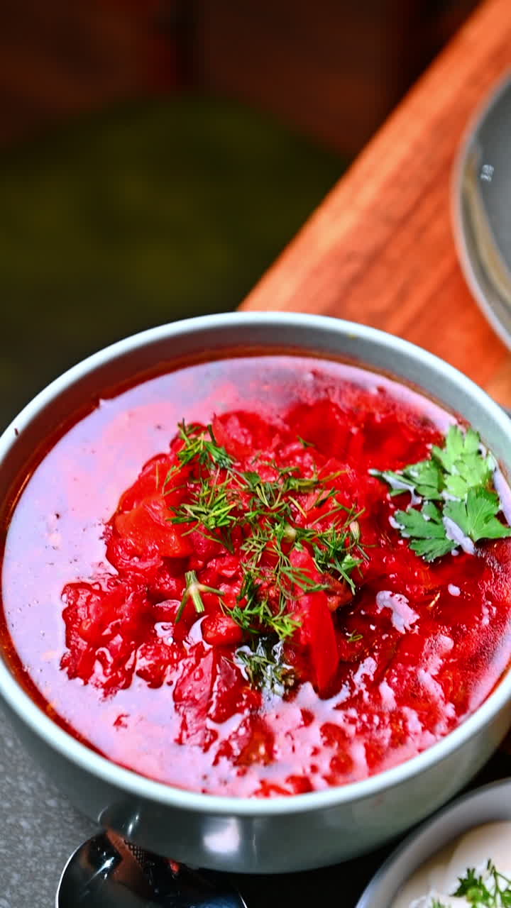 Vibrant beet soup in bowl. Bright beet based soup served warm with herbs and a smooth texture