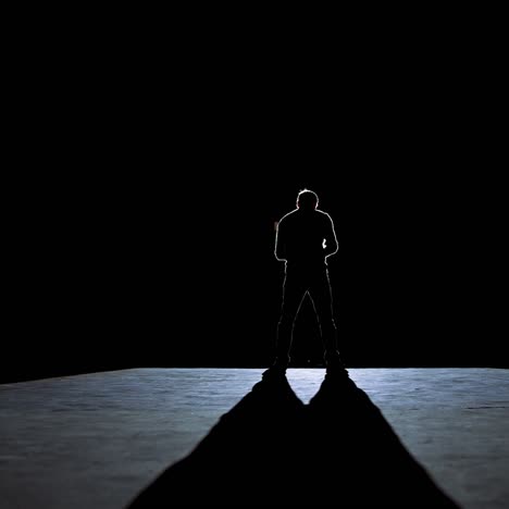 senior man in costume on stage in darkness. active man in hat dancing on stage during the performance in the theater